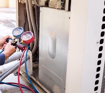 HVACR Repair Technician Measuring Freon Gas Pressures with Equipment HVAC technician checking refrigerant pressures with gauge set
