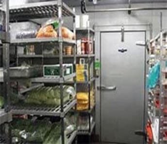 Inside view of a commercial walk-in refrigerator with shelves full of fresh food items.