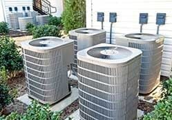 Cluster of four AC condensing units on the outside ground of a nice home during an AC Tune Up.