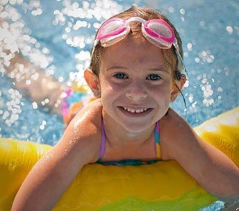 Kid Swimming and Having Fun in a Heat Pump Heated Pool Child enjoying a heated swimming pool powered by an energy-efficient heat pump