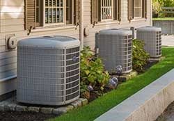 Three sleek condensing units on green grass by an upscale condo
